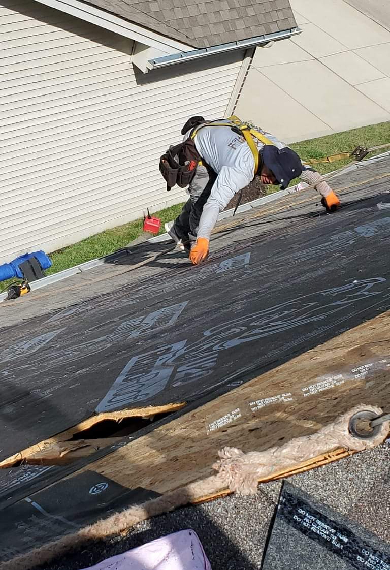 Worker repairing roof with safety harness