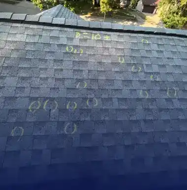 Close-up of hail damage marks chalked on asphalt shingles for an insurance inspection in St. Louis Metro area