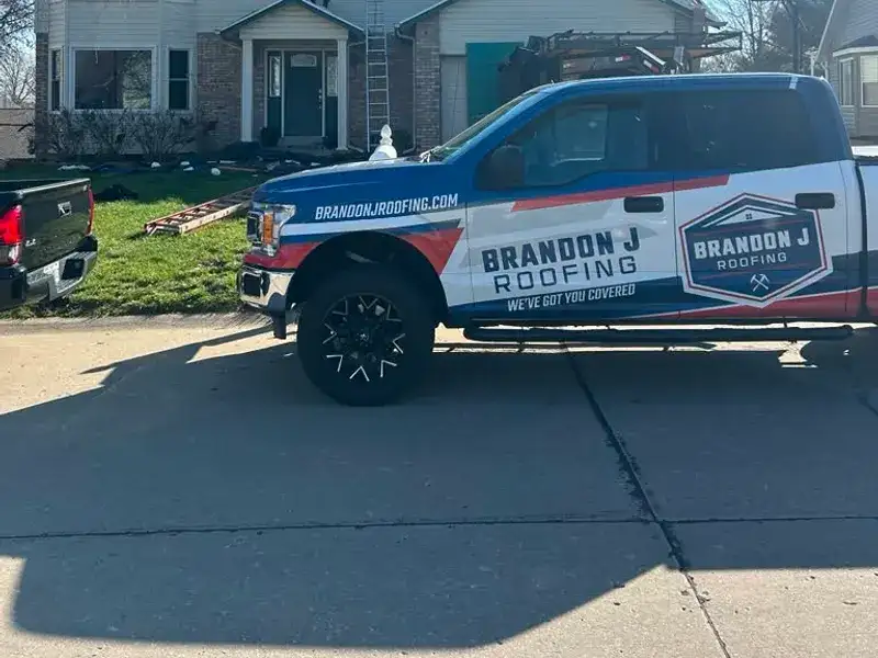 Brandon J Roofing truck parked at a residential job site during a roof tear-off