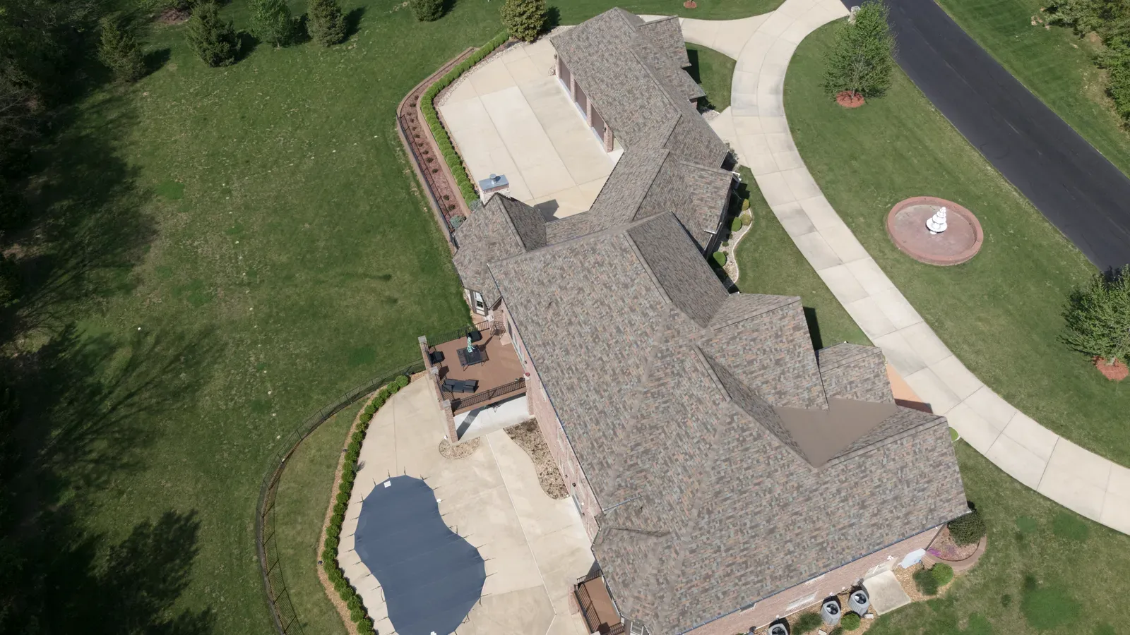 Aerial view of a completed brown shingle roof replacement on a custom home