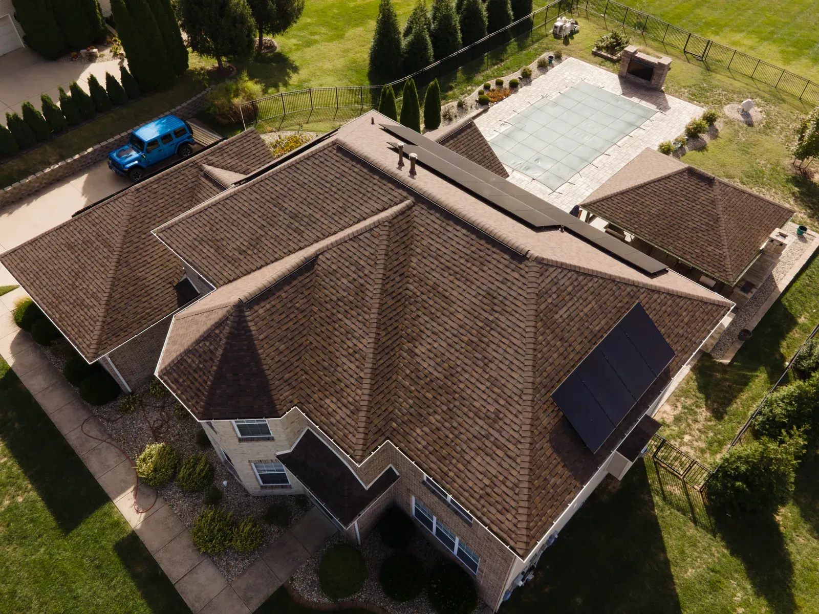 Aerial view of a brown shingle roof replacement with rooftop solar panels