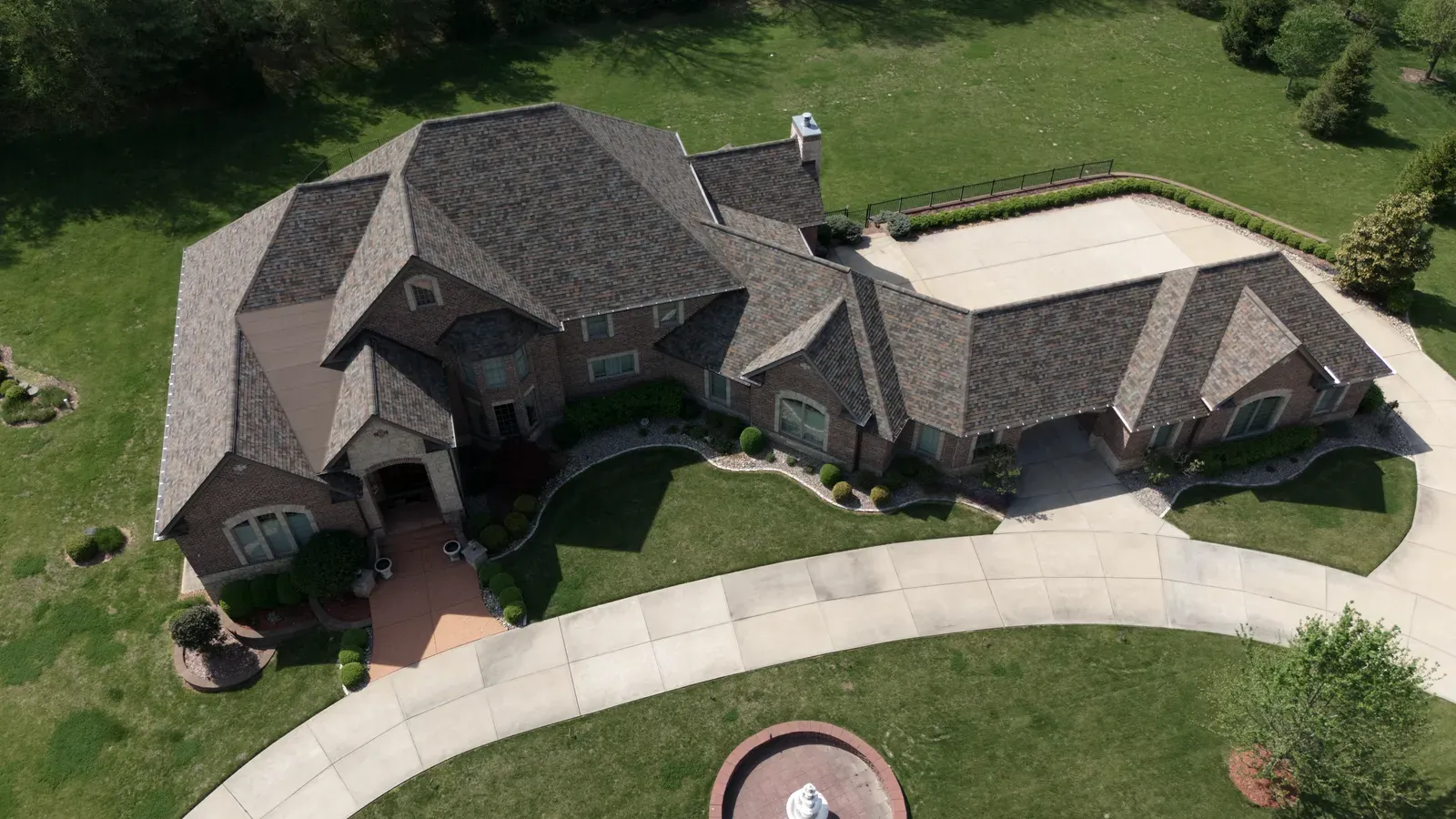 Aerial view of a large estate home with a new weathered-wood shingle roof