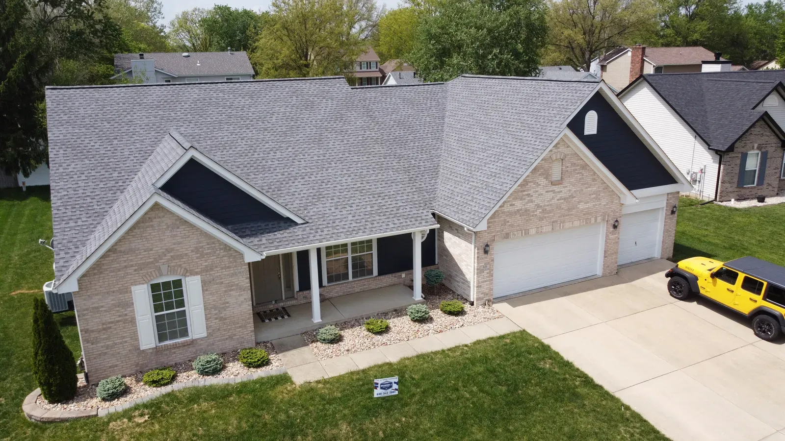 Aerial view of a new gray shingle roof on a ranch-style brick home