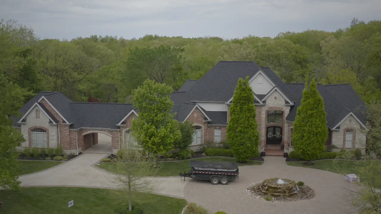 Aerial view of house with dark shingle roof.